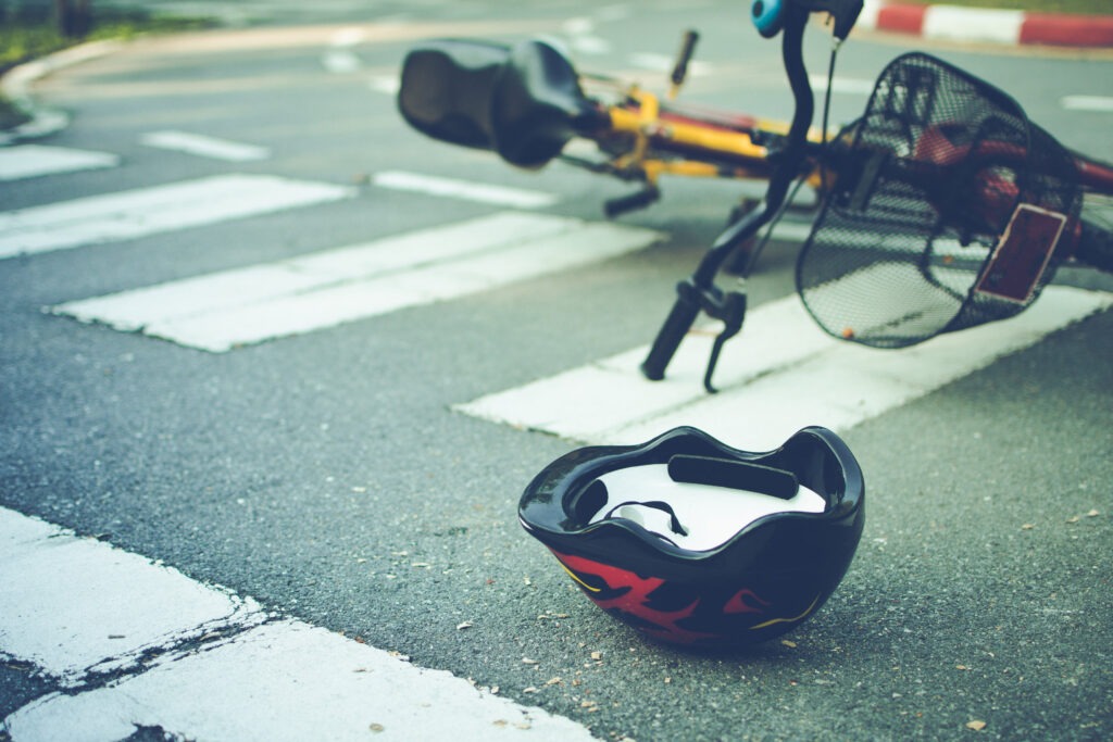 Helmet and bike lying on the road on a pedestrian crossing.